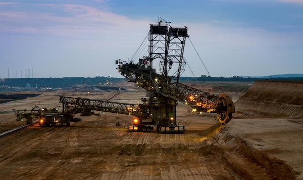 Bucket wheel excavator in the coal mine on the sunset. Huge coal mining drill machine in open pit