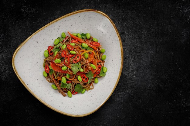 Buckwheat noodles with duck vegetables and hot pepper on a plate