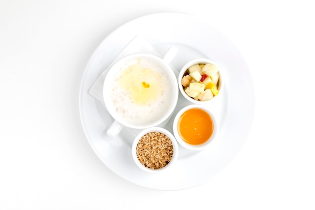 Photo buckwheat porridge with milk and butter in a white plate on a white background