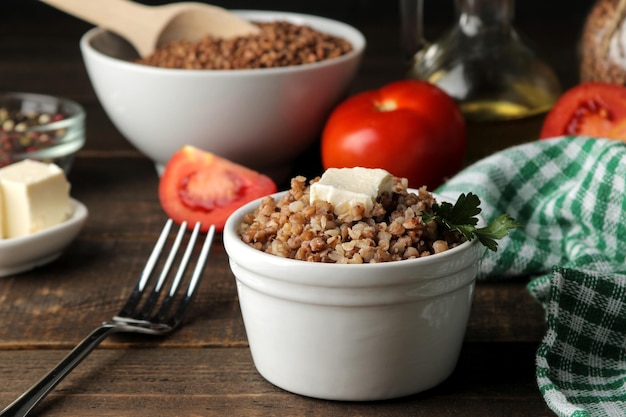 Buckwheat. Porridge with a piece of butter in a glass plate on a brown wooden table. breakfast, healthy food.