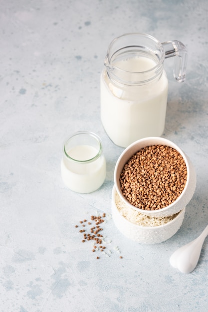 Buckwheat and rice in white bowls and milk jug. Healthy breakfast.