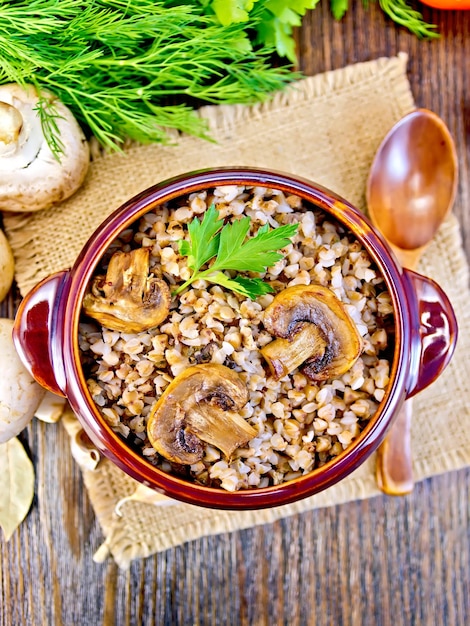 Buckwheat with champignons in clay bowl on table top