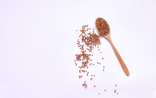 Buckwheat in a wooden spoon on white