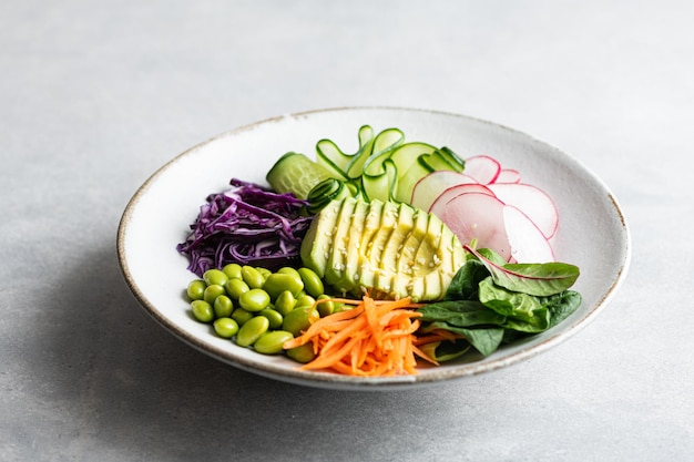 Buddha bowl with avocado edamame beans cucumber red cabbage carrots radishes and spinach vegetable s