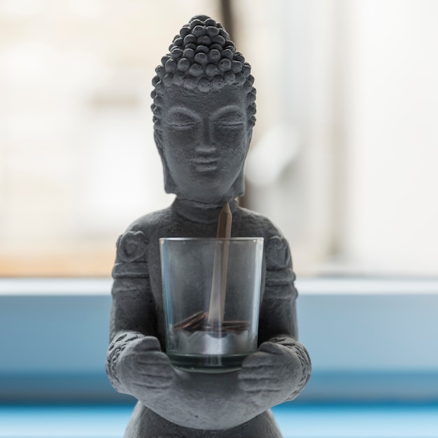 Buddha of cement with glass with coins and a pencil