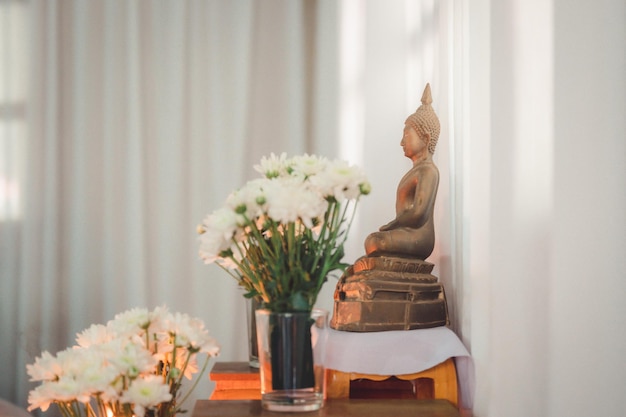 Buddha statue with flowers and white background