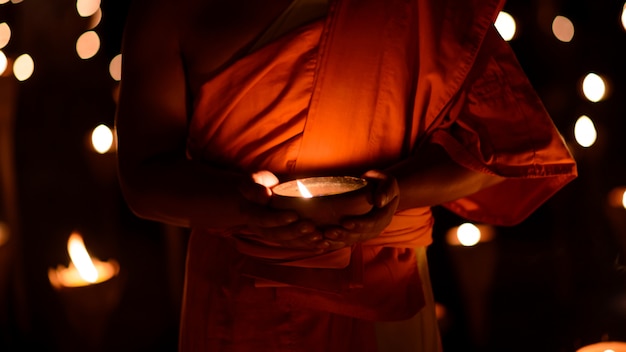 Photo buddhist monk hands holding candle cup in the dark ,chiang mai , thailand