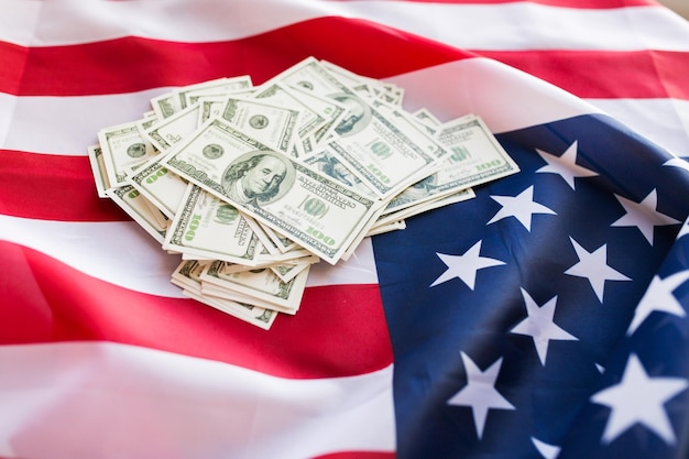 budget, finance and nationalism concept - close up of american flag and dollar cash money