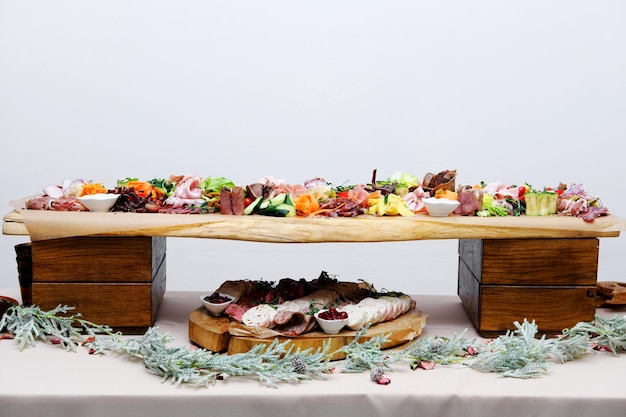 Buffet table with cold appetizers Meat and vegetable snacks are placed on wooden stands