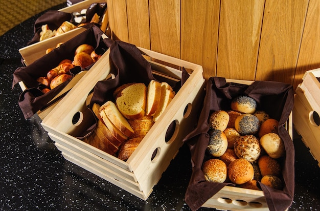 A buffet table with variety of bread in the wooden baskets