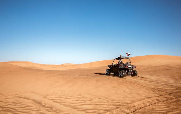 Buggy quad bike driving in Dubai desert safari with Emirates flags and traces