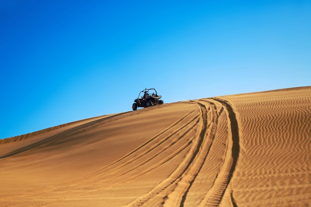 Buggy quad drive on desert sand hill and leave wheel tracks