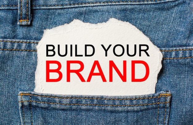 Build Your Brand on torn paper background on jeans business and finance concept