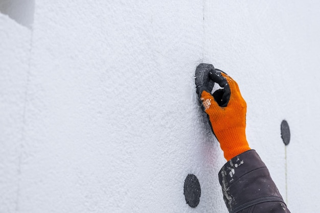 Builder installs styrofoam insulation sheets reinforces them and fills the gaps with foam