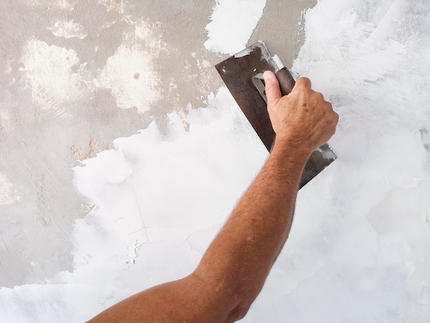 Builder using plastering tool for finishing old wall.