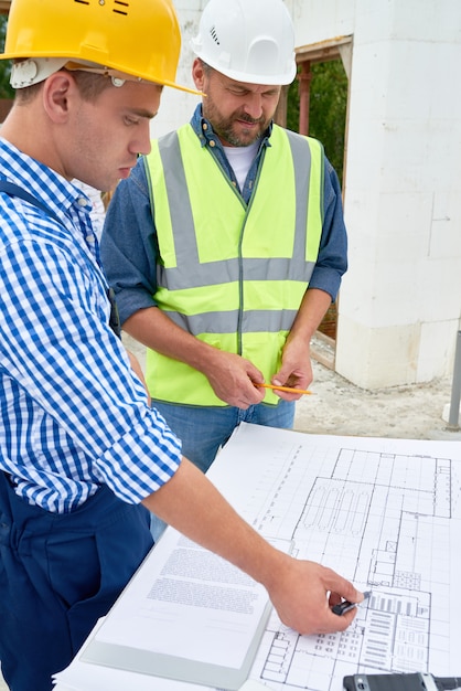 Builders Checking Floor Plans on Construction Site