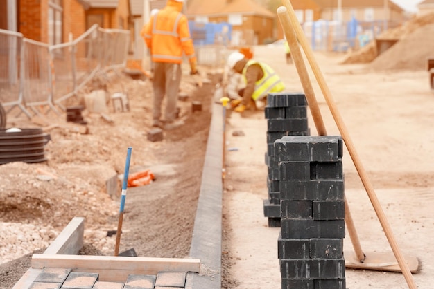 Builders installing paving blocks during road and footpath construction on a semidray concrete mix