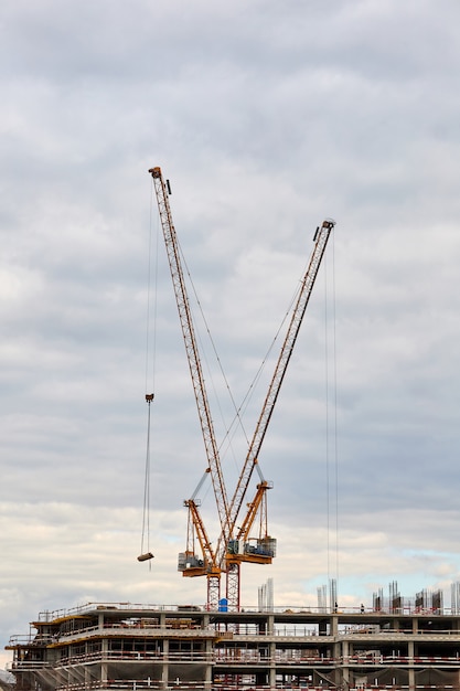 Building under construction and tower cranes against the sky