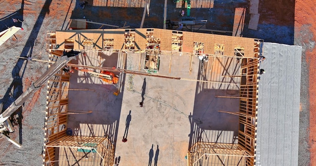 Building contractor carpenter placing new building wood engineered trusses on a residential under co