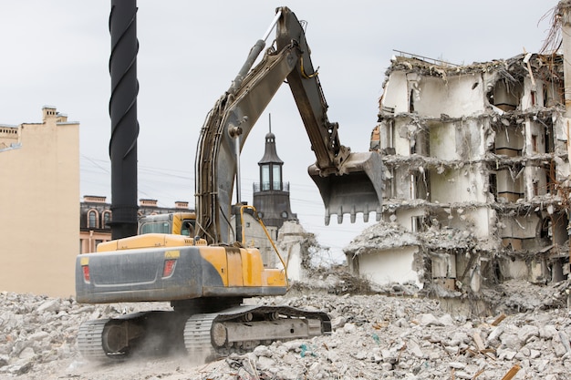 Building of the former hotel demolition for new construction, using a special hydraulic excavator-destroyer. Dismantling of house.