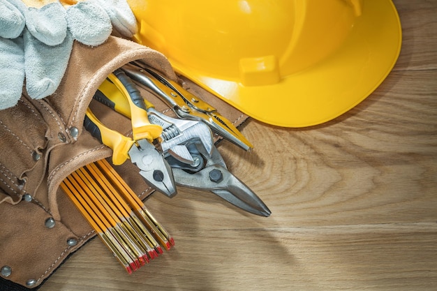 Building helmet safety gloves tool belt tooling on wooden board