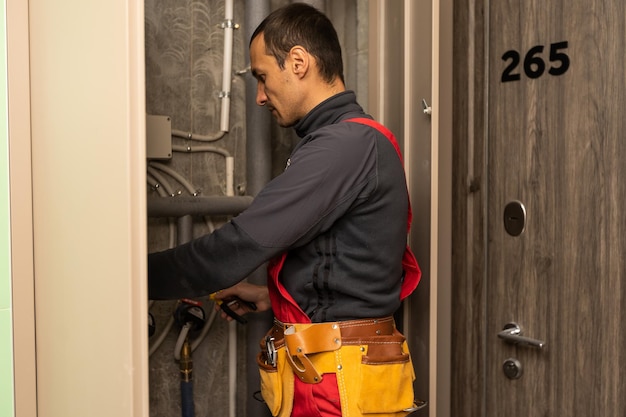 building, profession and people concept - builder or plumber working with water pipes in boiler room.