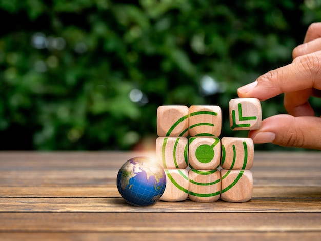 Building success goal business Last block holding by hand putting on target icon on wood block stack puzzle near 3d earth on green background Global green business process plan management concepts