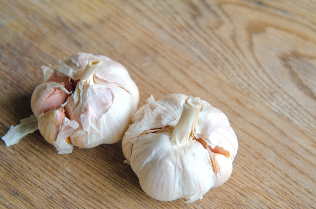 Bulbs of organic garlic and garlic cloves on natural wooden background