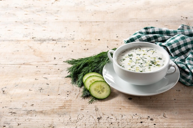 Bulgarian tarator sour milk soup in bowl on wooden table.