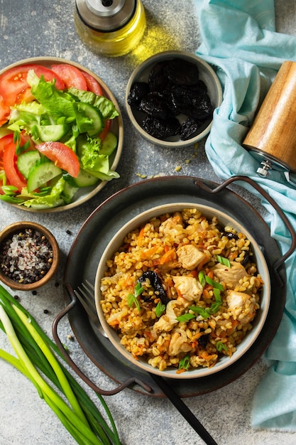 Bulgur with chicken vegetables and prunes on a gray stone or slate countertop Top view