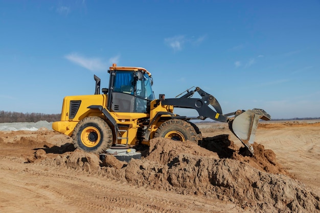 Bulldozer or loader moves the earth at the construction site against the blue sky An earthmoving machine is leveling the site Construction heavy equipment for earthworks