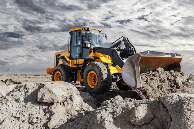 Bulldozer or loader moves the earth at the construction site against the sunset sky Contrasting image of a modern loader or bulldozer Construction heavy equipment for earthworks