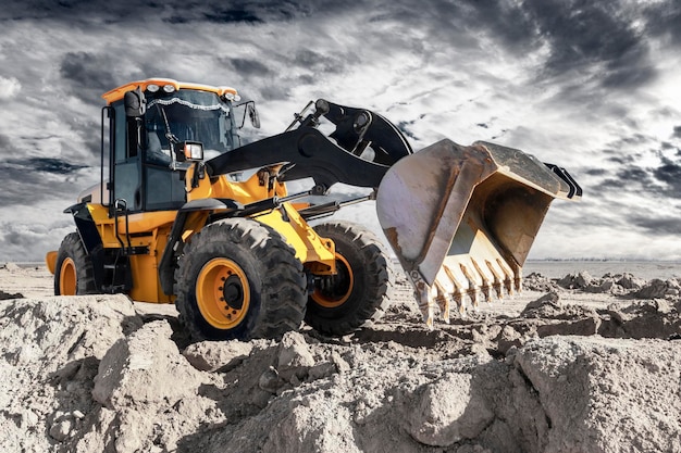 Bulldozer or loader moves the earth at the construction site against the sunset sky Contrasting image of a modern loader or bulldozer Construction heavy equipment for earthworks