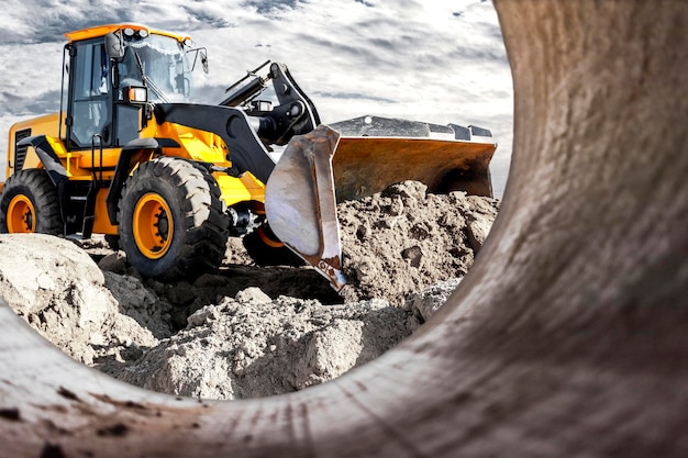 Bulldozer or loader moves the earth at the construction site against the sunset sky Contrasting image of a modern loader or bulldozer Construction heavy equipment for earthworks