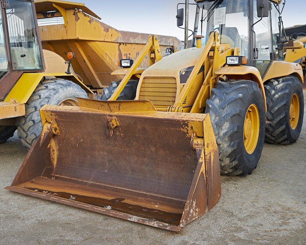 Bulldozers at a construction site parked after operating Huge orange powerful building vehicle with a hydraulic piston scoop and black wheels Heavy machinery outside in an empty space