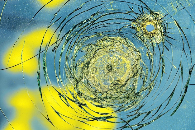 Bullet hole cracks in the glass on a yellowblue background Concept Russian Ukrainian War