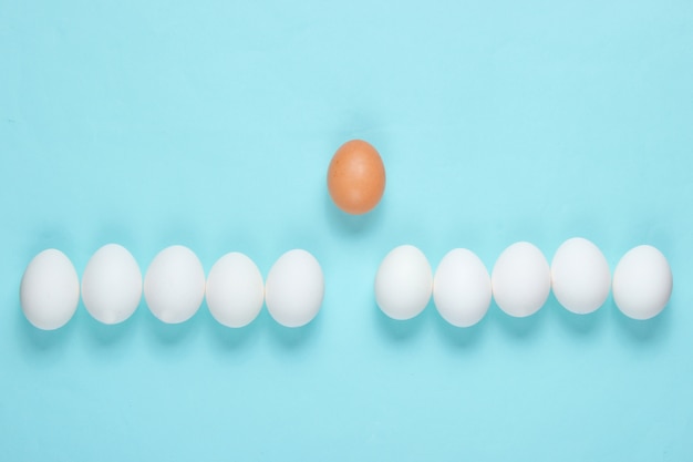 Bullying concept with eggs on a blue table. Top view, minimalism