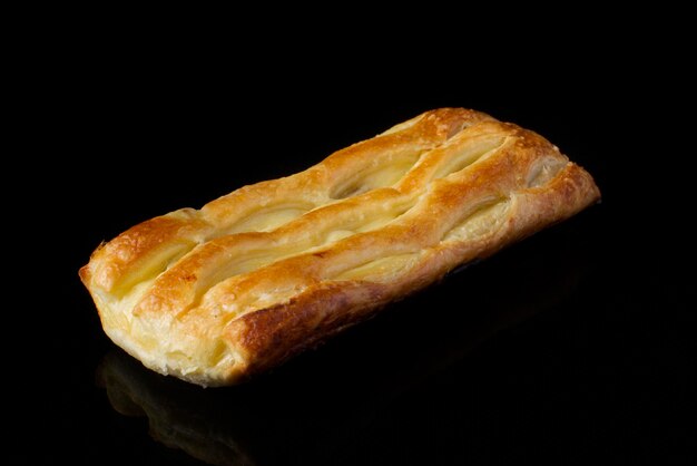 Bun with puff pastry with cottage cheese on a dark background