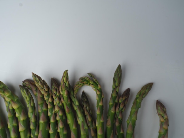 A bunch of asparagus that is laying on a white surface.