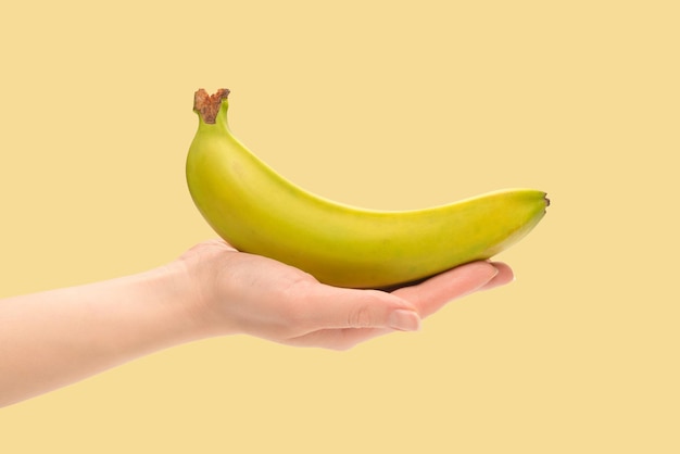 A bunch of bananas in woman hand isolated on yellow background