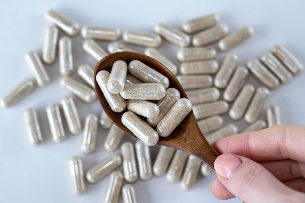 A bunch of beige herbal remedies or dietary supplements in a wooden spoon