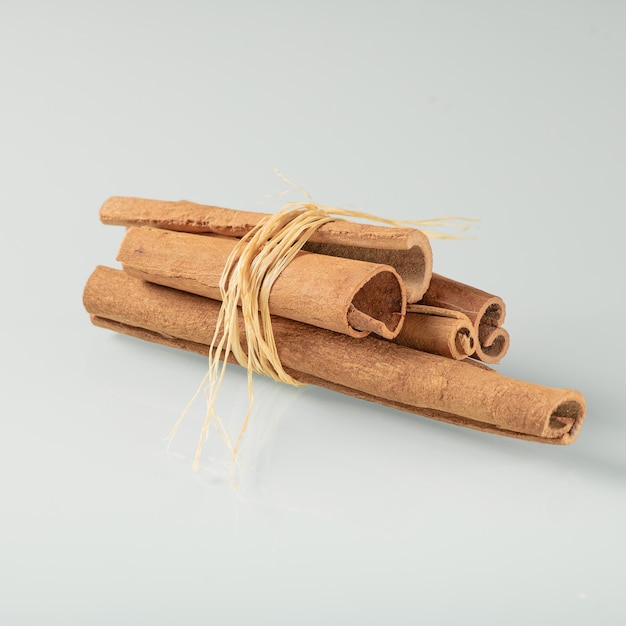 Bunch of cinnamon sticks on a light background with reflection in a glass background