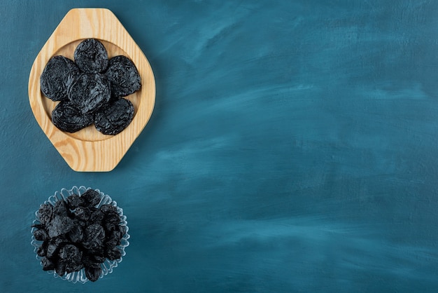 Bunch of dried apricots, plums and raisins on blue table.