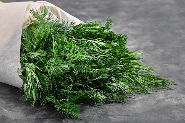 A bunch of fresh dill in craft paper on a stone surface. Useful and useful dill.