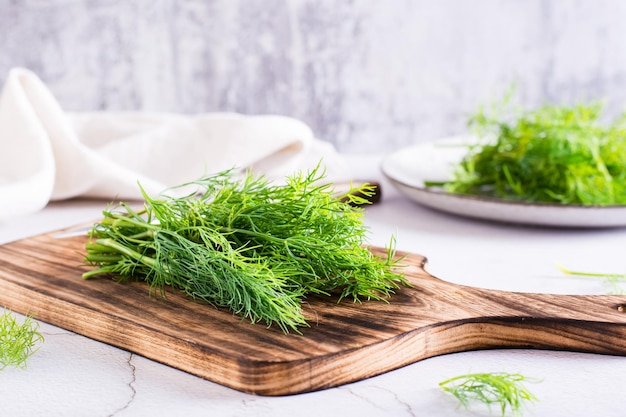 A bunch of fresh dill on a cutting board on the table Organic seasoning