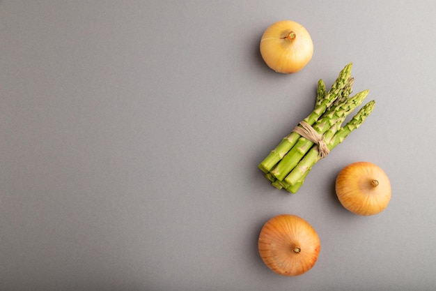 Bunch of fresh green asparagus and onion on gray pastel background Top view copy space