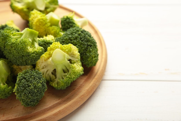 Bunch of fresh green broccoli on cutting board on white wooden background. Top view.