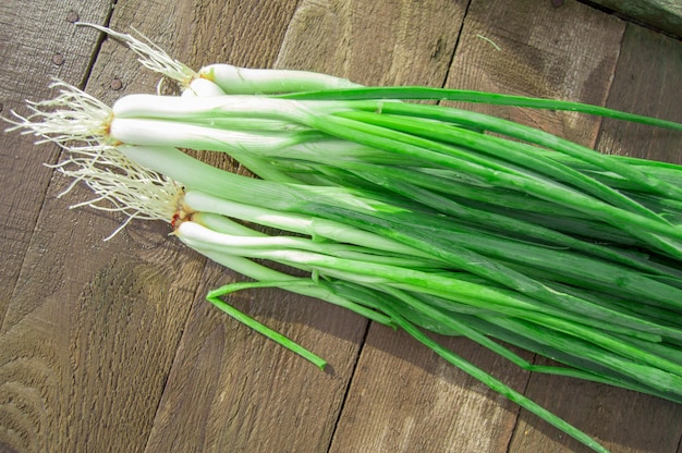 Bunch of fresh green onions on an old wooden table