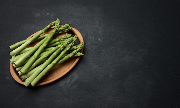 Bunch of fresh raw asparagus on a wooden black kitchen board a healthy product