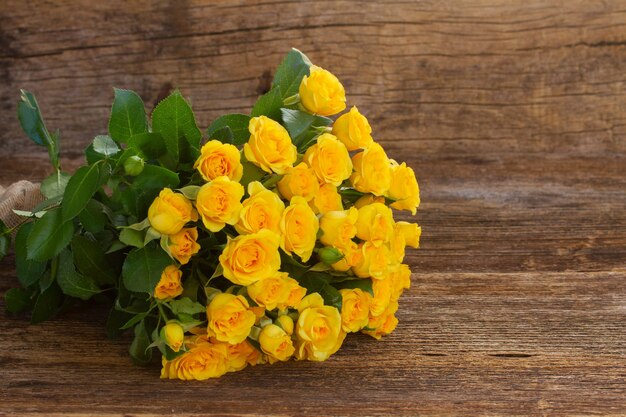 Bunch of fresh yellow roses on wooden